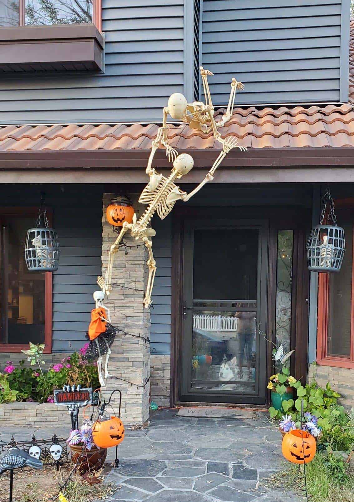 halloween decorated front porch with skeletons climbing the roof
