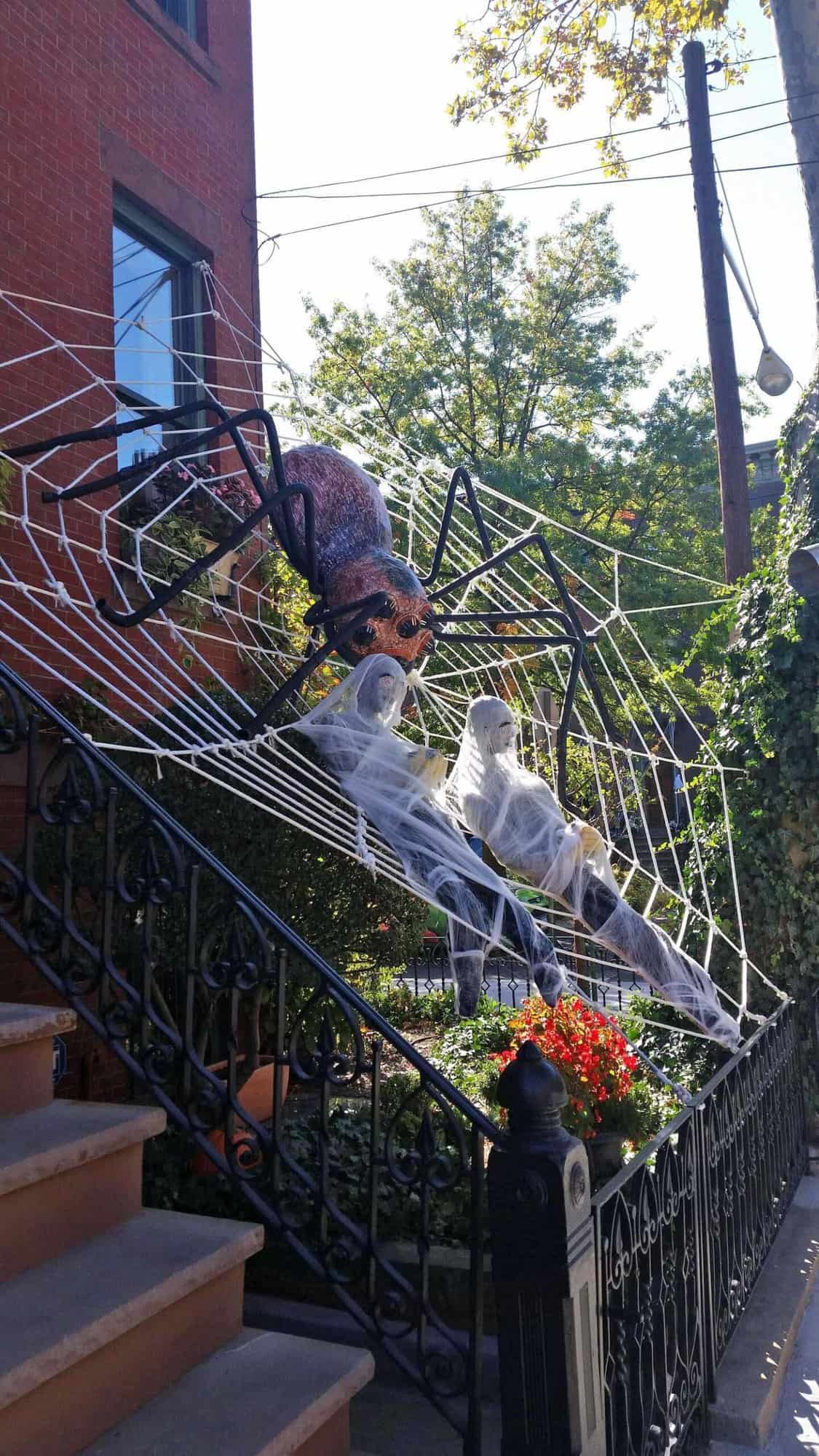 front porch halloween decor with a giant spider and web with mummies