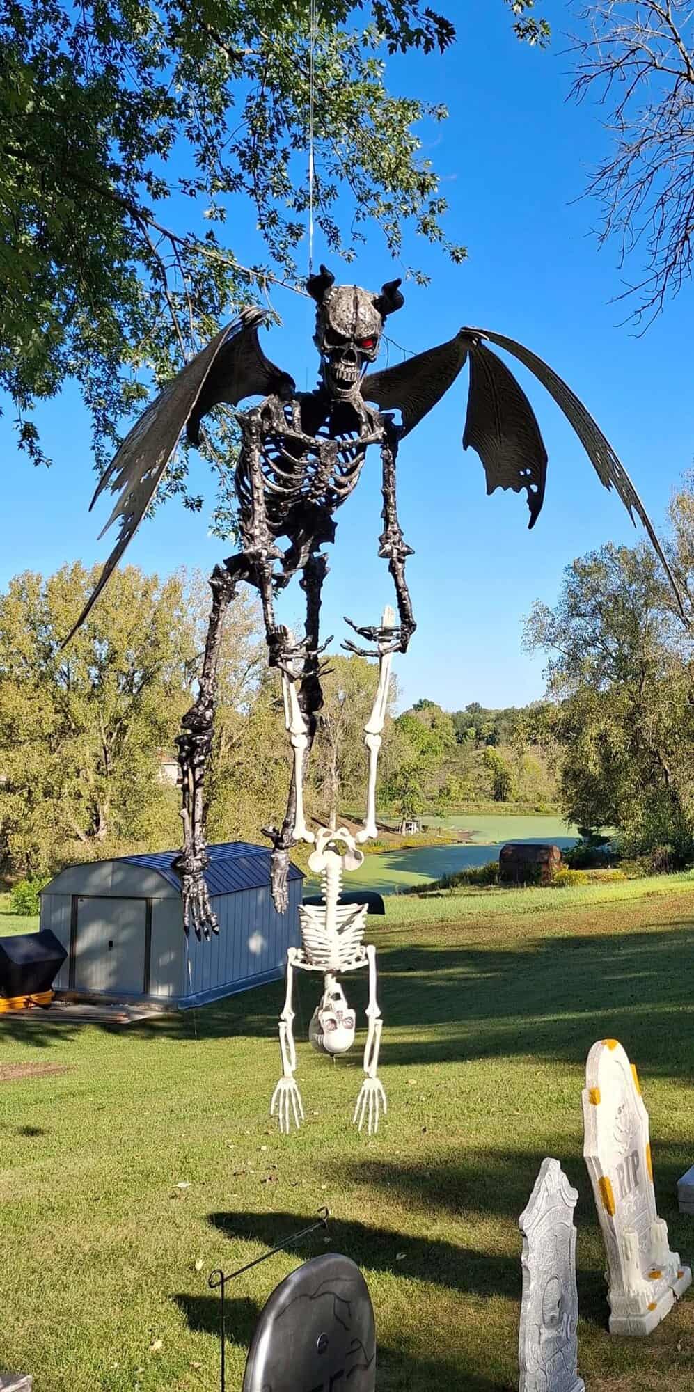 halloween yard decorations with a winged demon holding a skeleton upside down