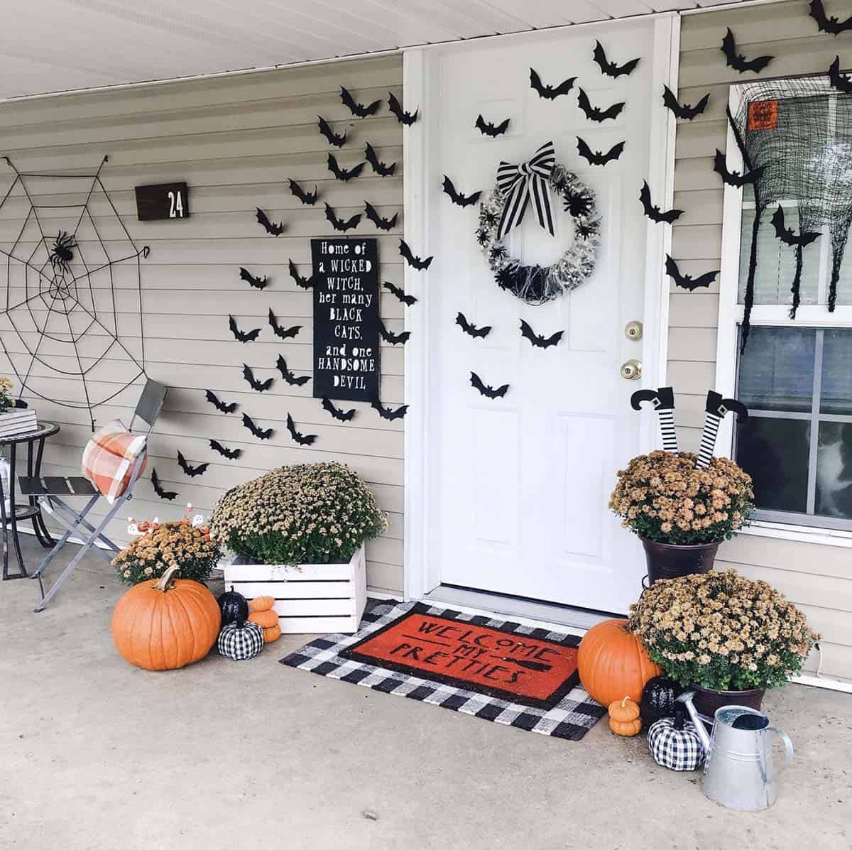 halloween decorated front porch with bats, pumpkins and mums
