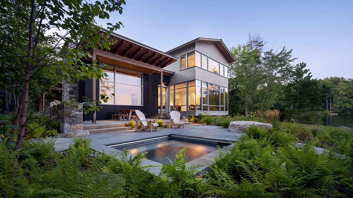 lake house exterior with a hot tub at dusk