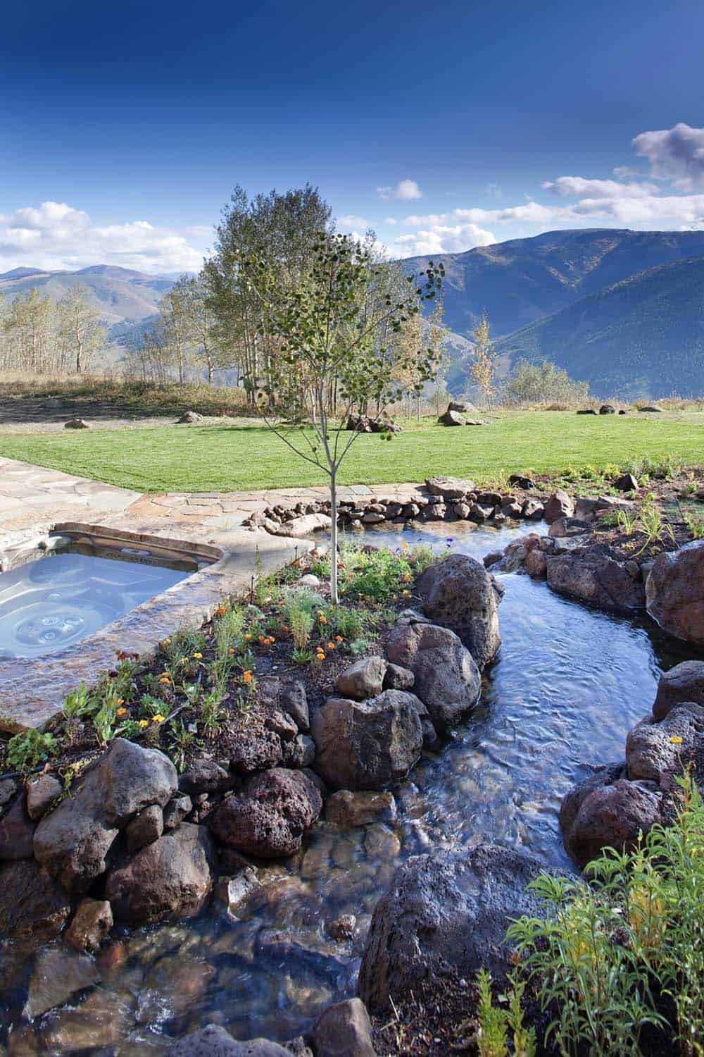 rustic mountain home exterior with a water feature and hot tub