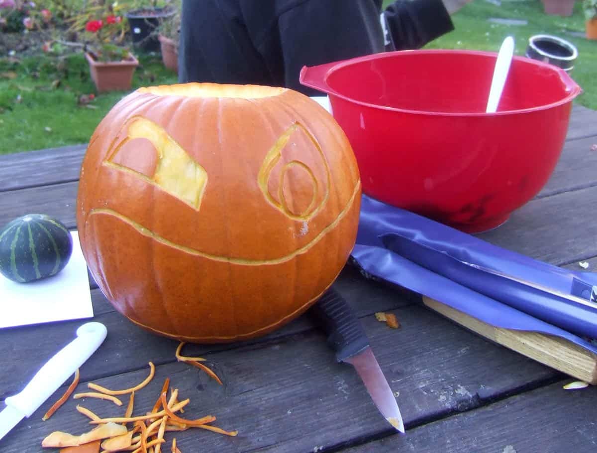 large pumpkin carving with a small green pumpkin in its mouth