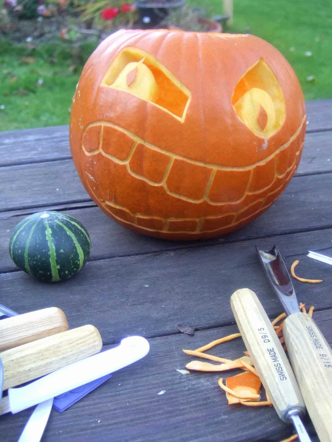 large pumpkin carving with a small green pumpkin in its mouth