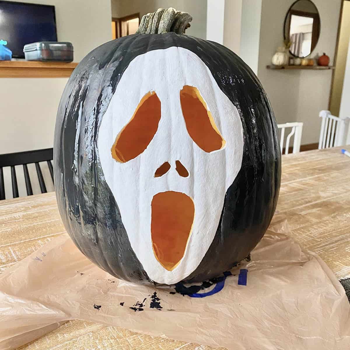 carved pumpkin with a painted ghost face