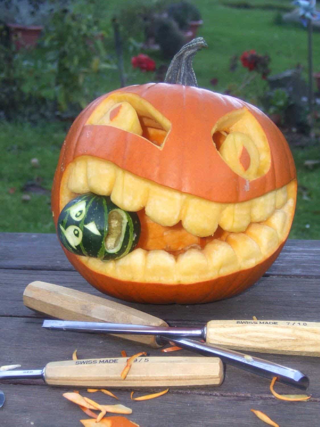 large pumpkin carving with a small green pumpkin in its mouth