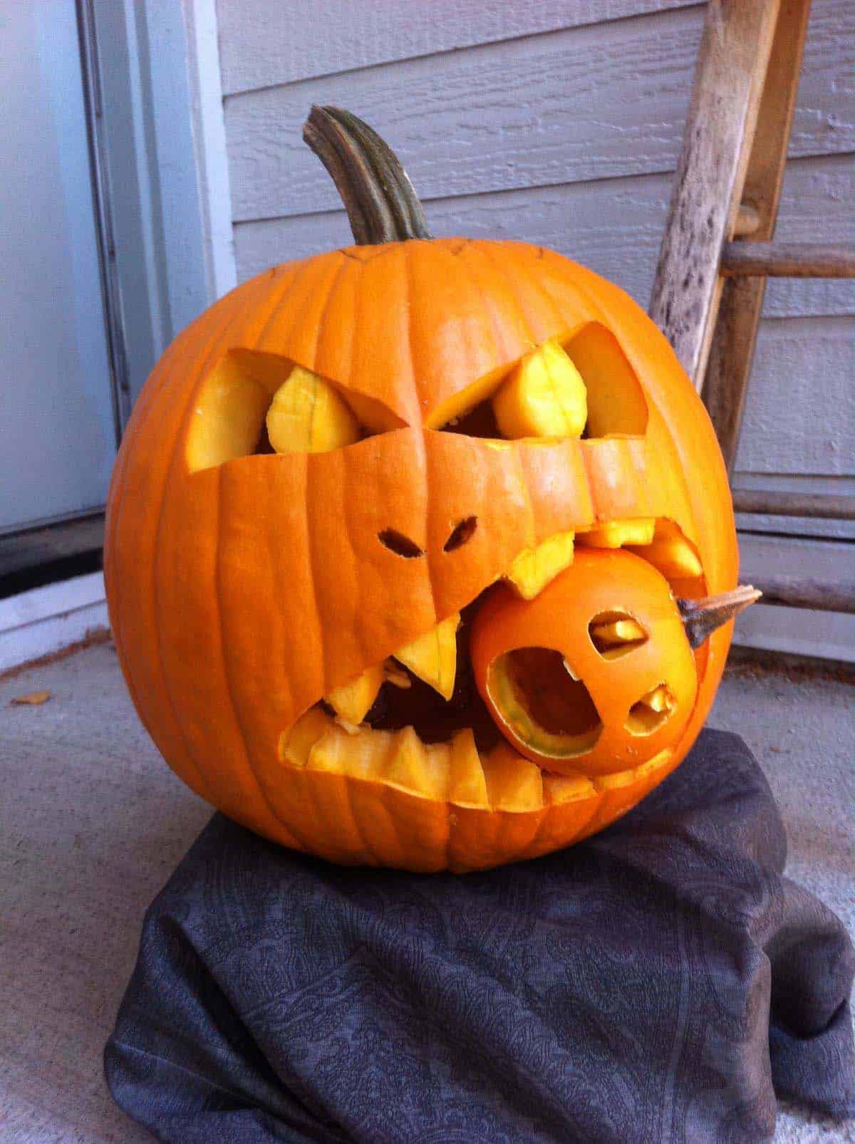 large pumpkin head with a small pumpkin in its teeth for halloween