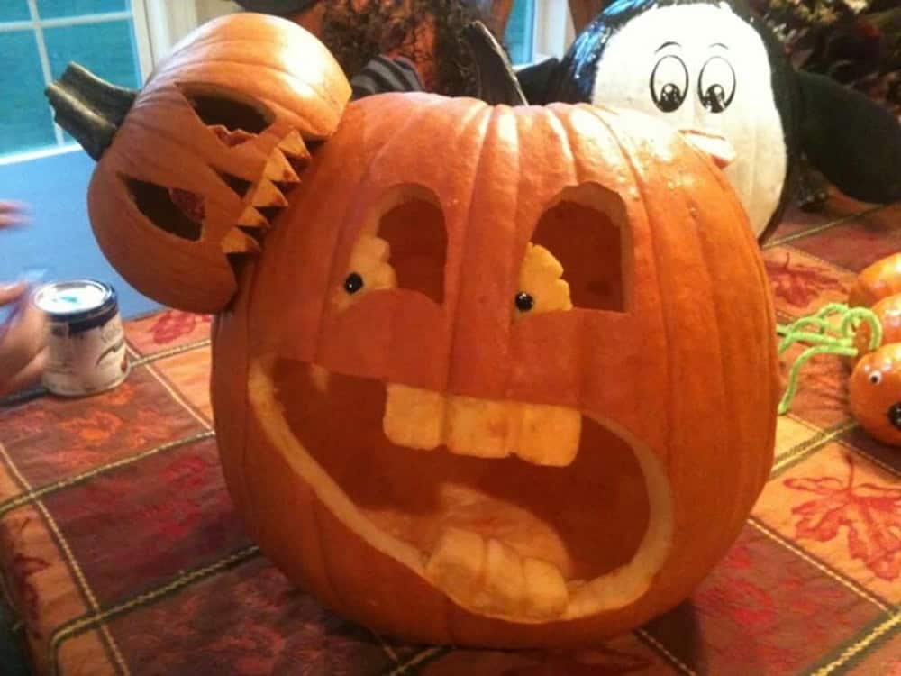 small pumpkin eating a large halloween carved pumpkin
