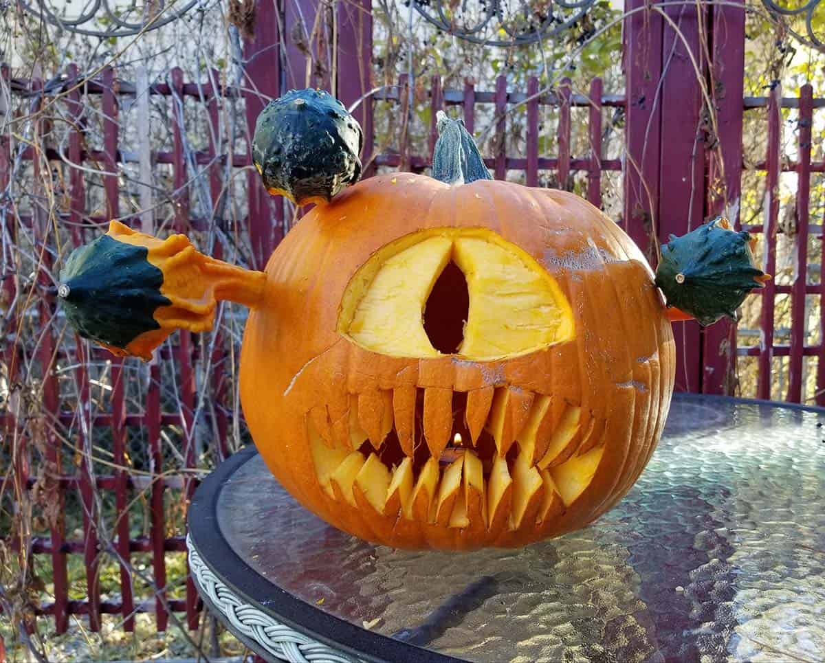 large pumpkin with one eye and gourds coming out of its head
