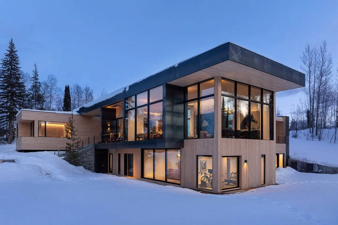 contemporary mountain house exterior with snow at dusk
