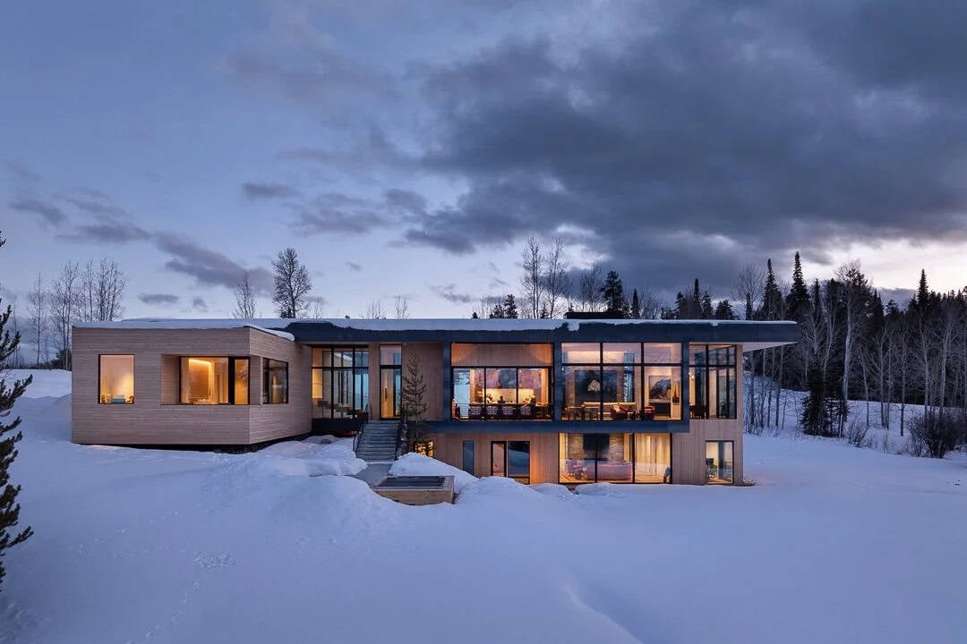 contemporary mountain house exterior with snow at dusk