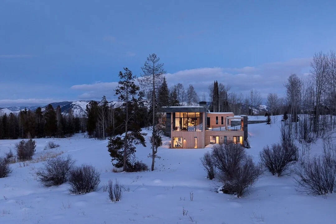 contemporary mountain house exterior with snow at dusk
