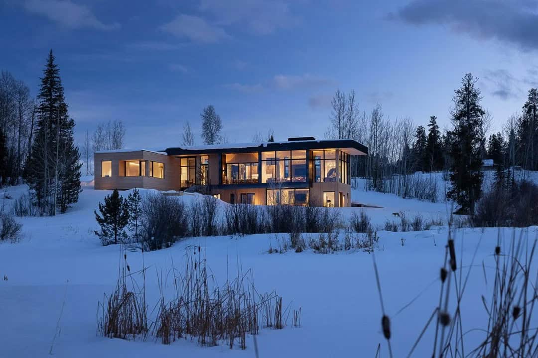 contemporary mountain house exterior with snow at dusk