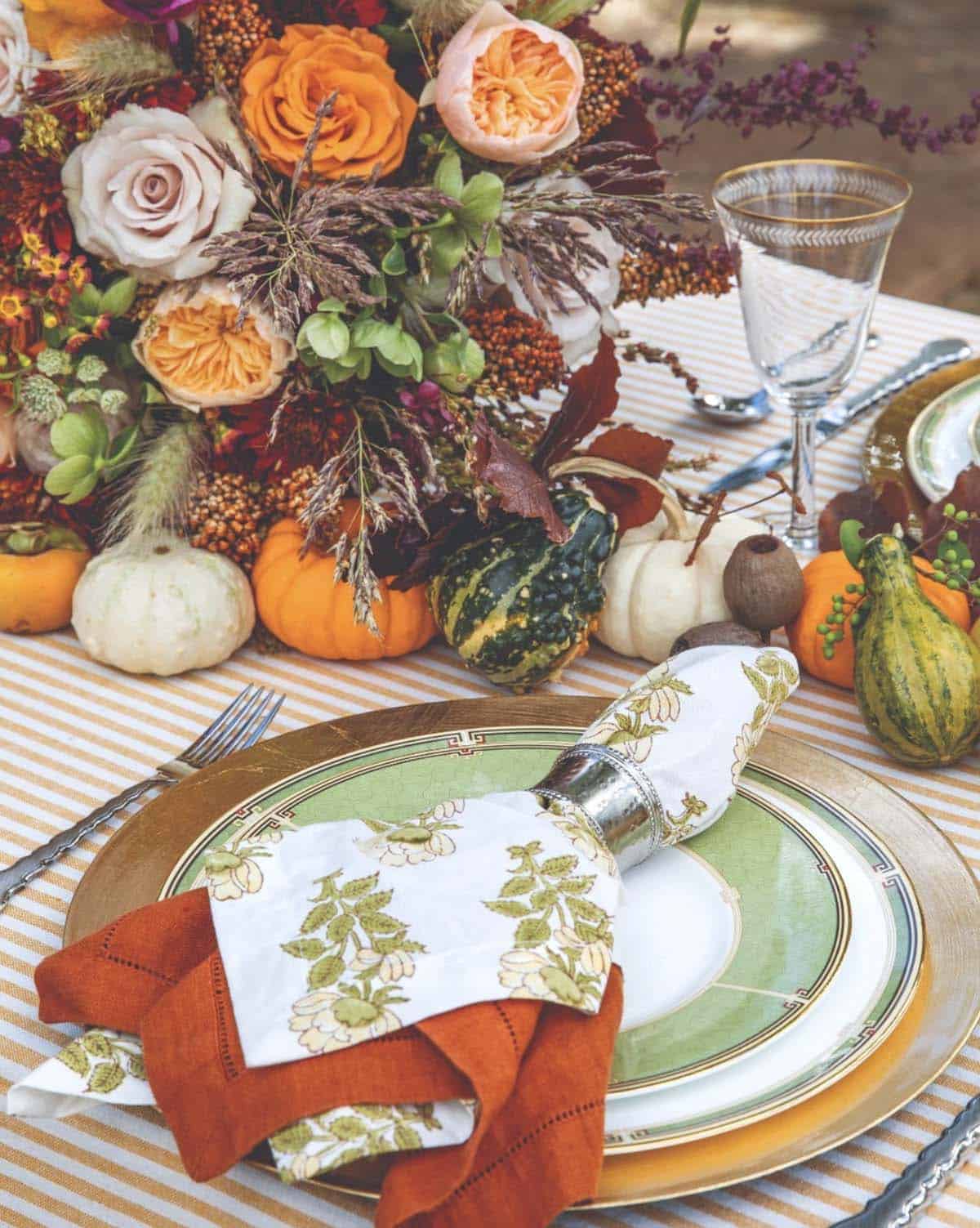 thanksiving table decor with pumpkins, gourds and a flower arrangement