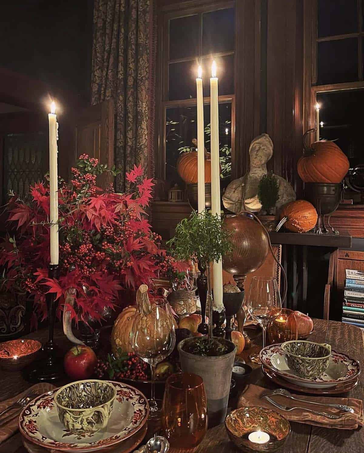 thanksgiving table with candles, pumpkins and a large floral arrangement