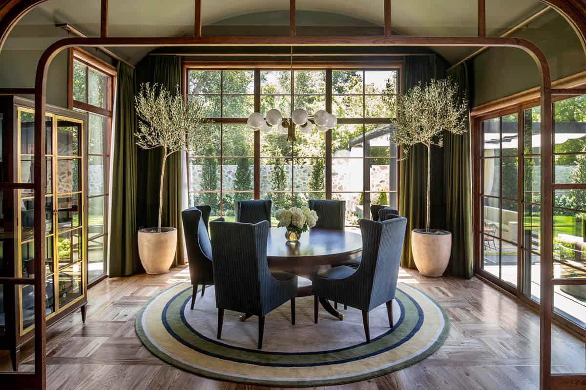 Elegant dining room with large windows and greenery views, modern lighting, and stylish accents.