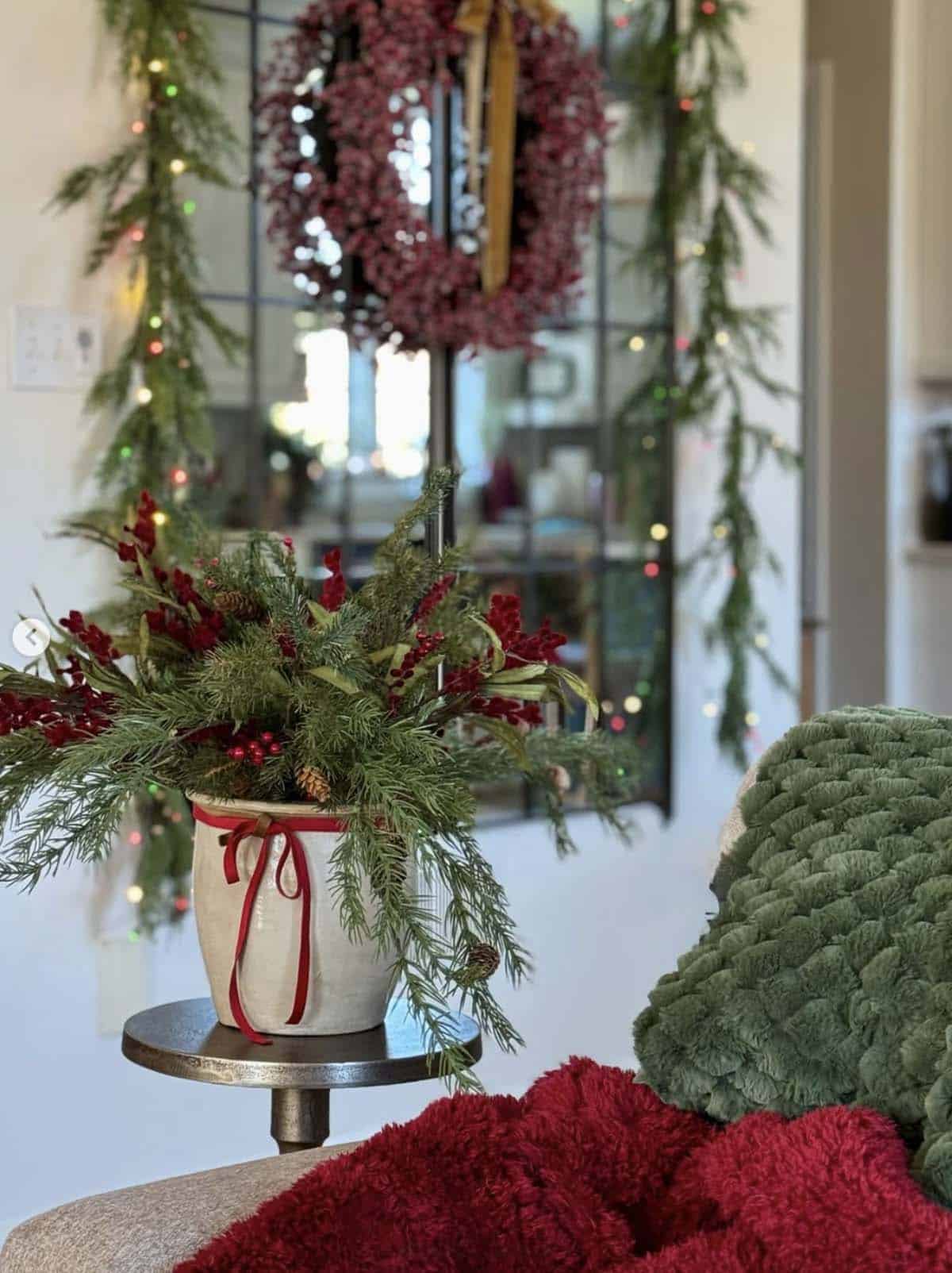 small table decorated for christmas with a vase filled with pine branches