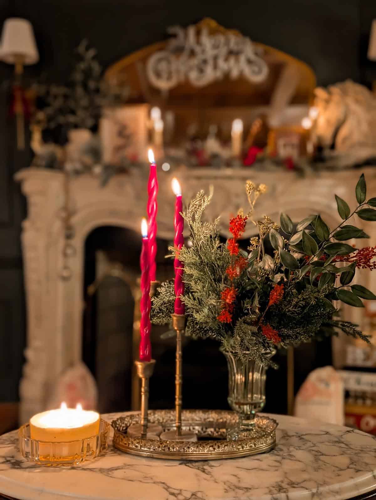 small tray with red candles and a vase filled with christmas flowers