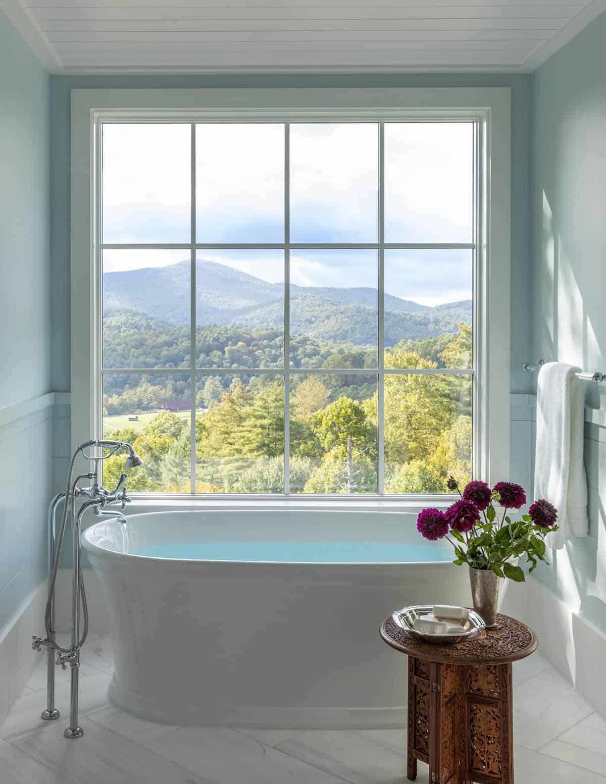 refined rustic bathroom with a freestanding tub and large picture window
