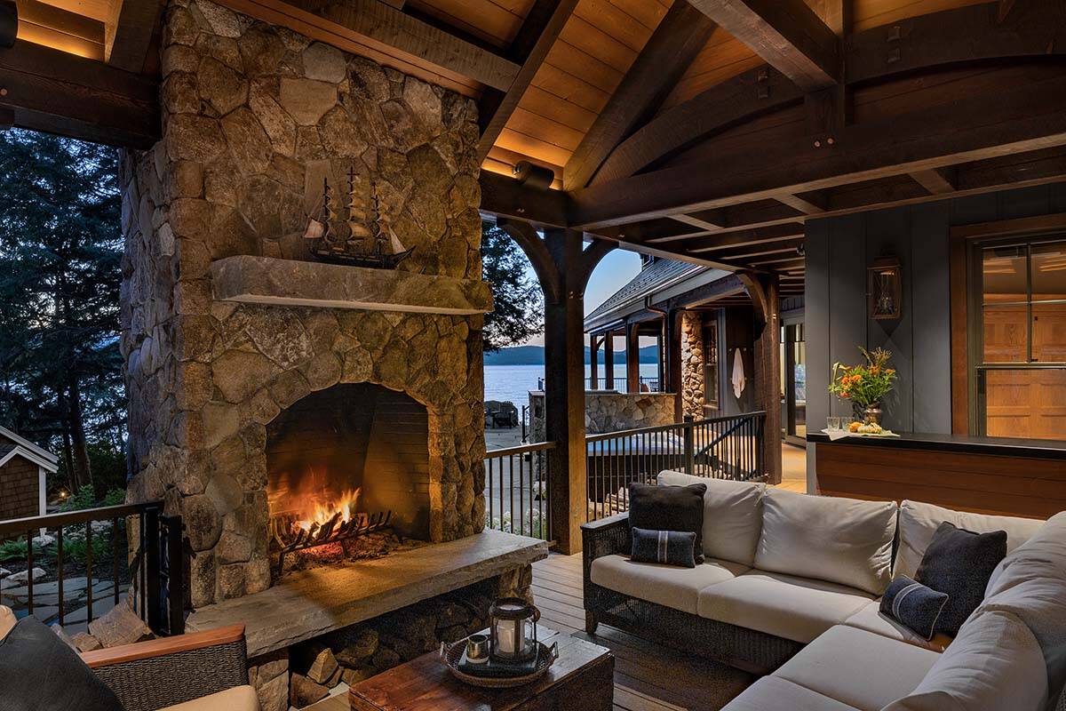 modern rustic covered porch with a fireplace at dusk