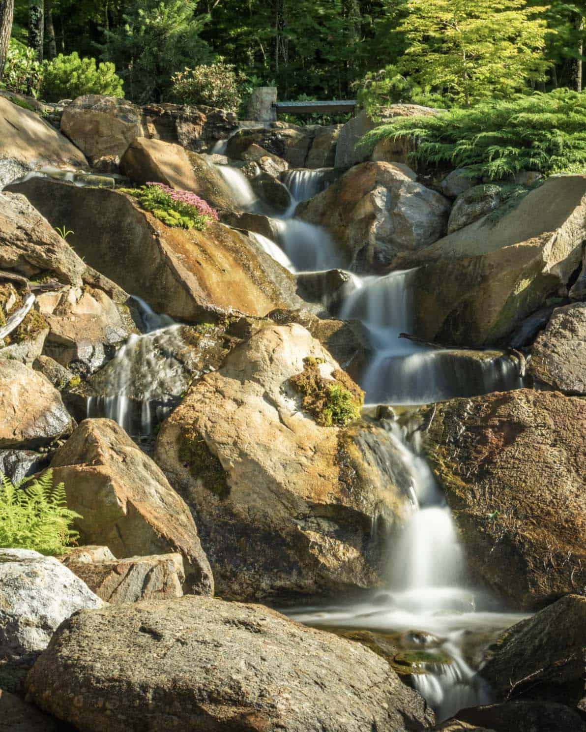 traditiional lake house exterior landscape with a waterfall