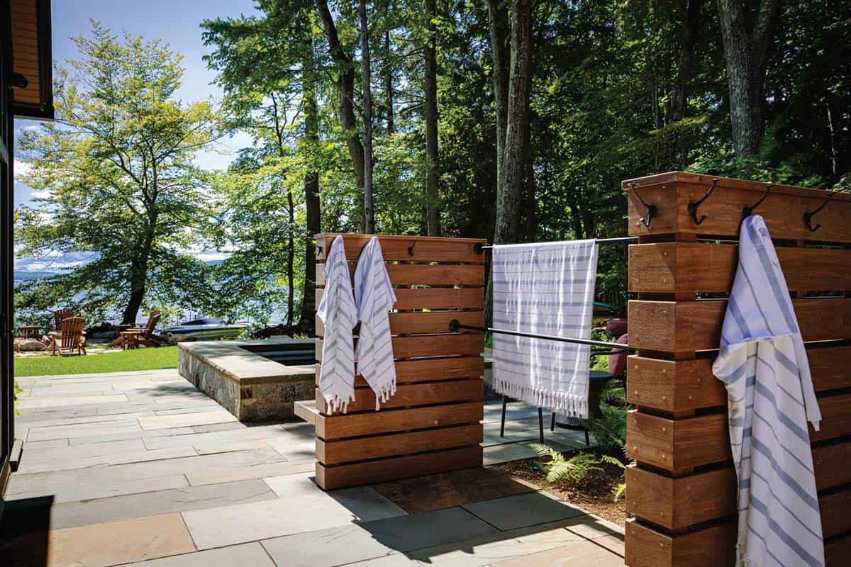 lake house exterior patio with a hot tub and towel storage hangers