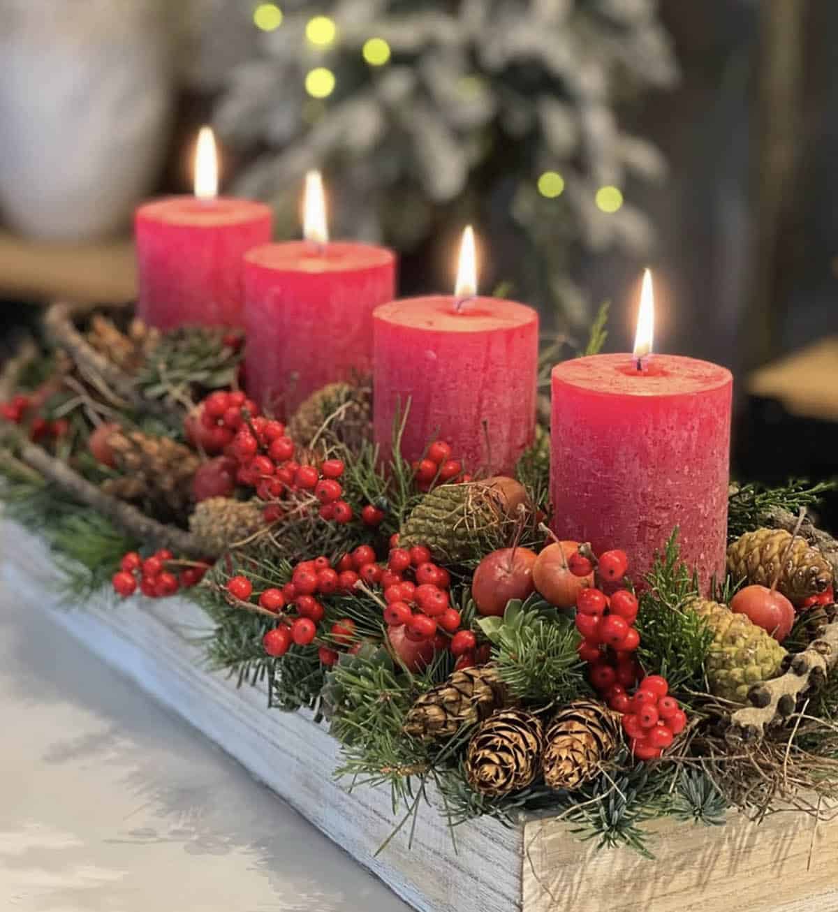 tray centerpiece with red candles, berries, greenery, and pinecones