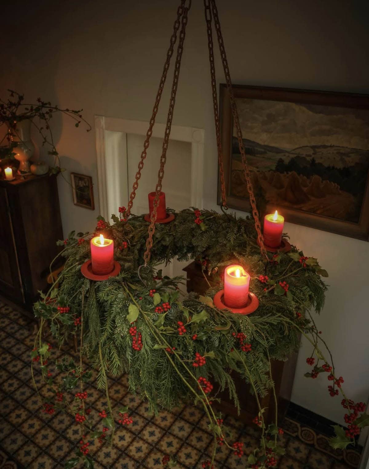 christmas decorated chandelier with greenery and red candles