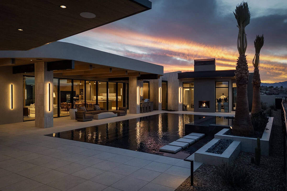 modern desert home exterior with a pool at dusk