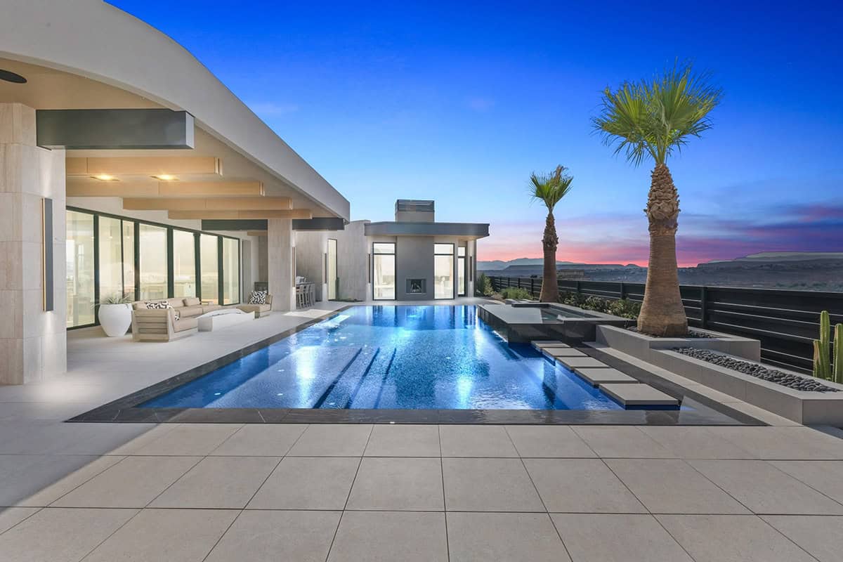 modern desert home exterior with a pool at dusk