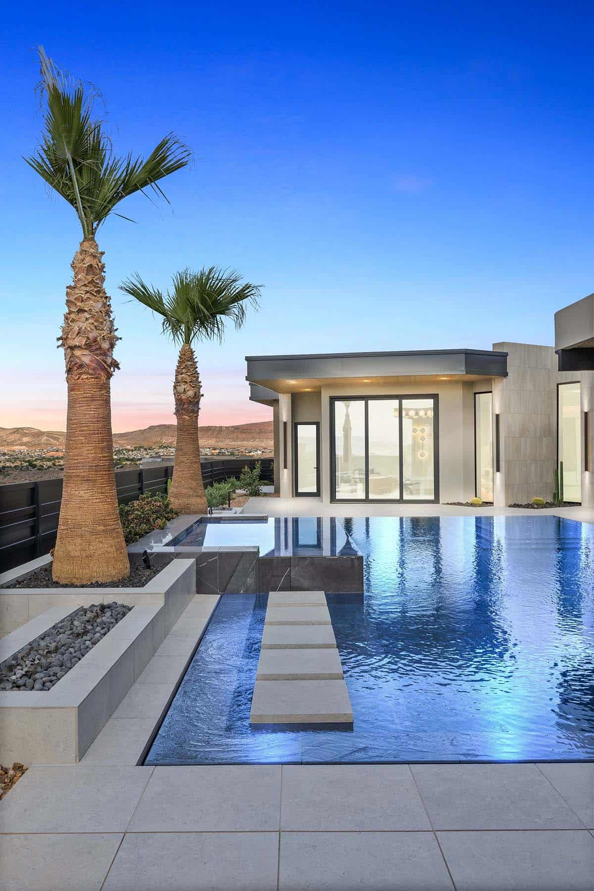 modern desert home exterior with a pool at dusk