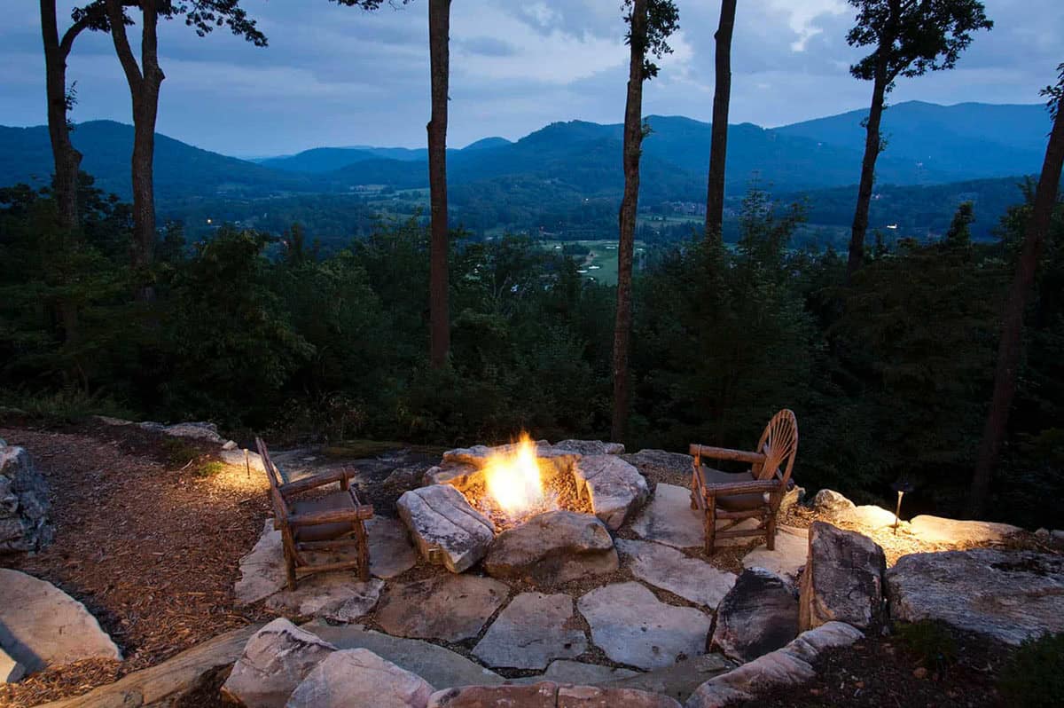 mountain rustic home exterior patio with a fire pit at dusk