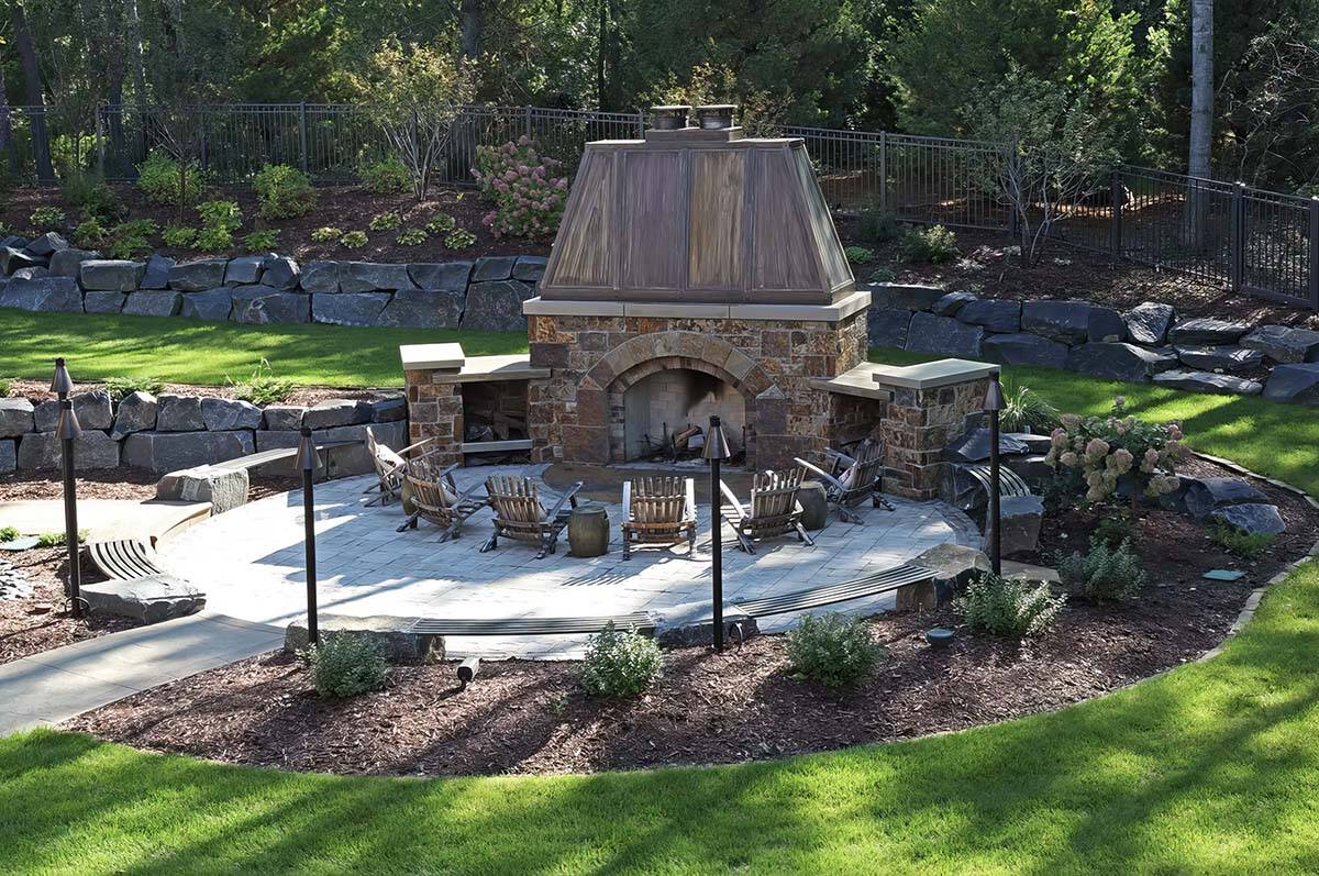 old world lodge style home exterior patio with a backyard fireplace