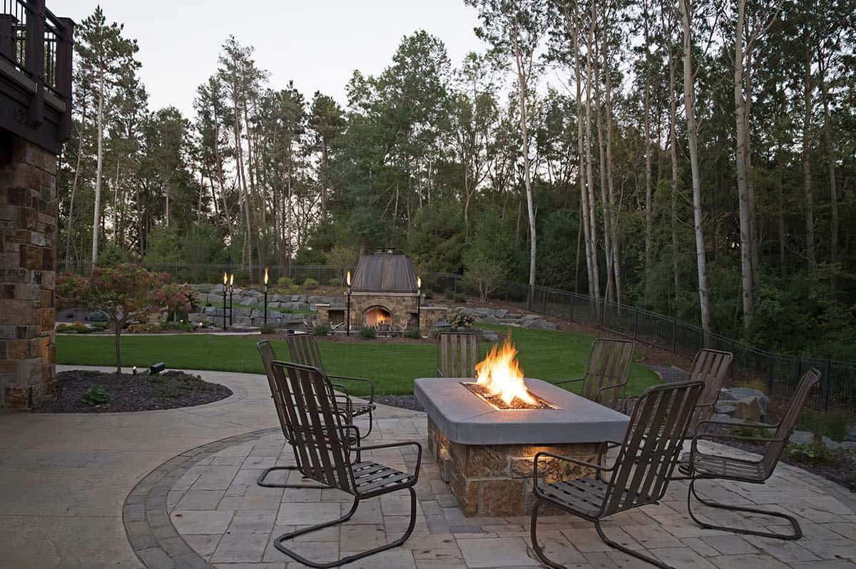 old world lodge style home exterior patio with a fire table