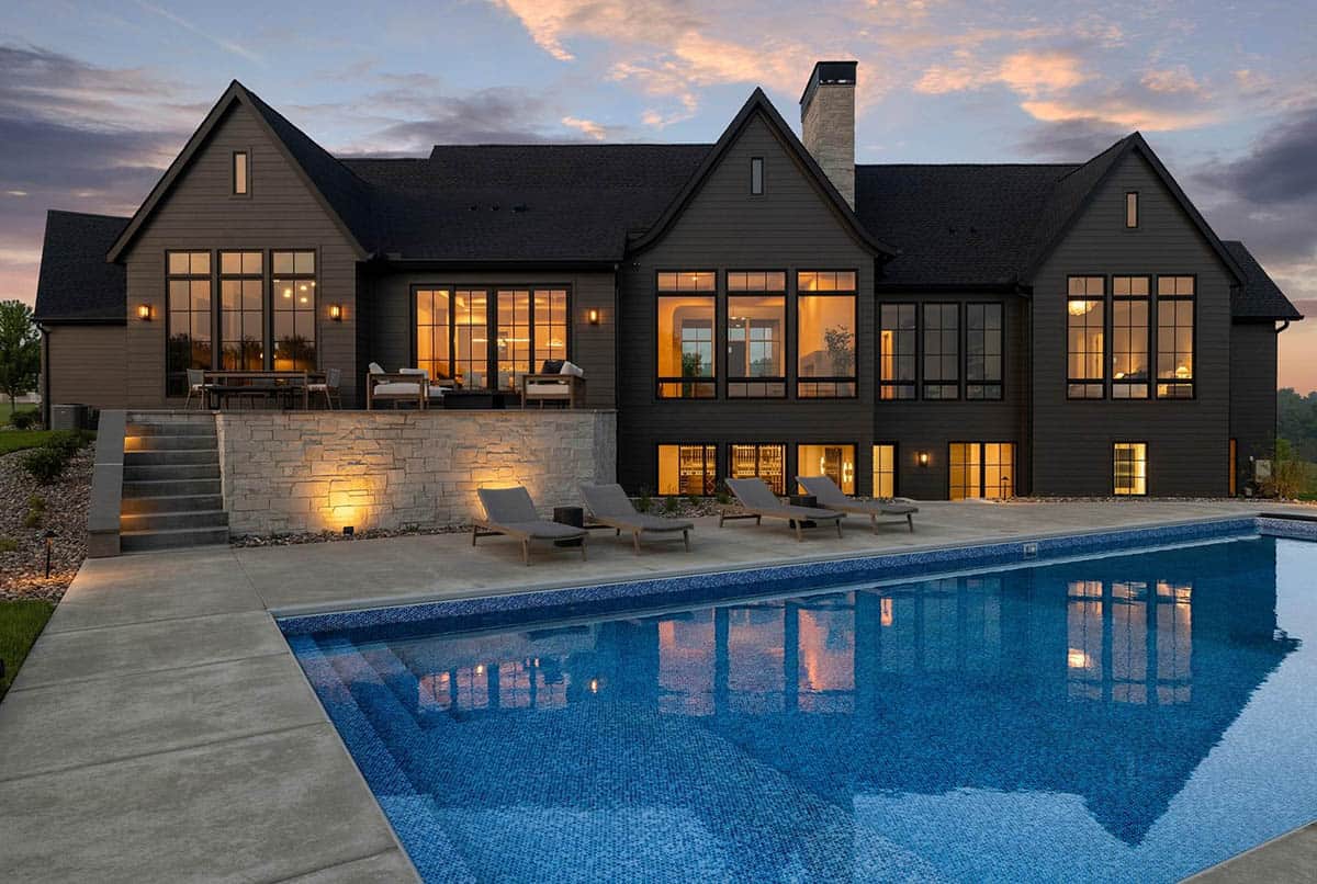 rambler style house exterior with a pool at dusk