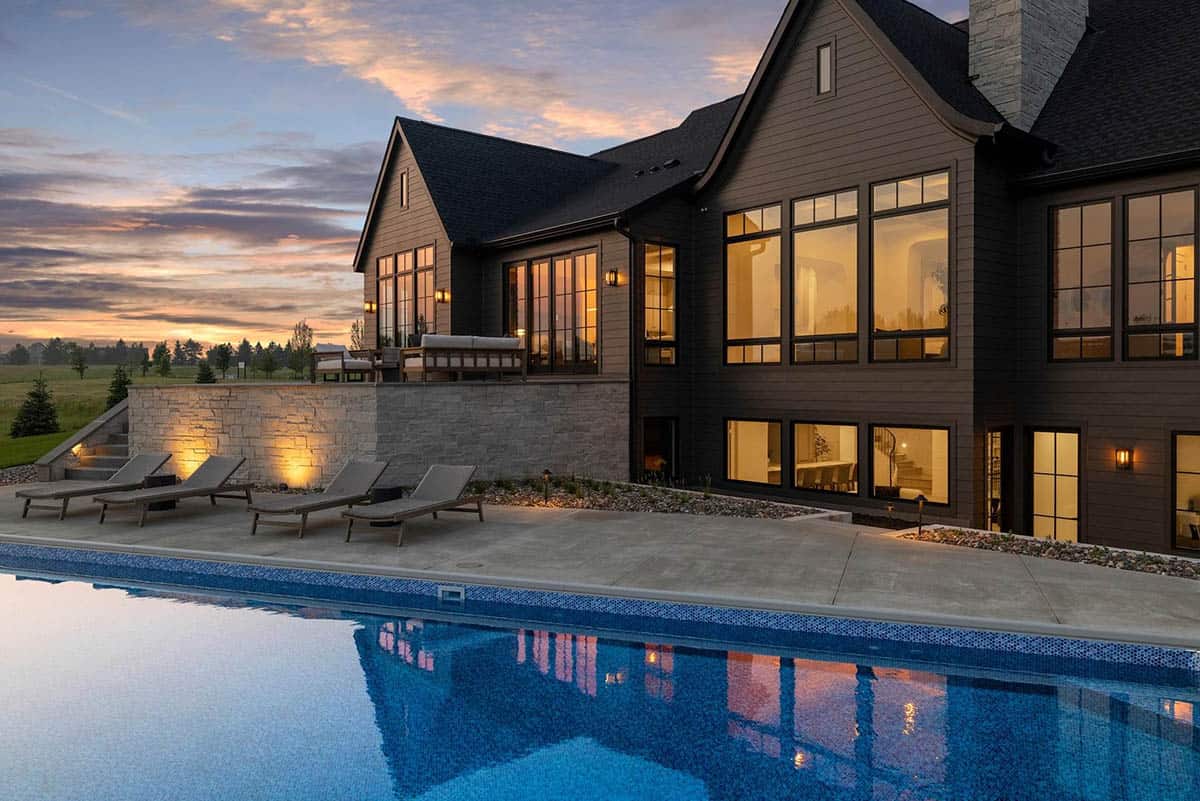 rambler style house exterior with a pool at dusk