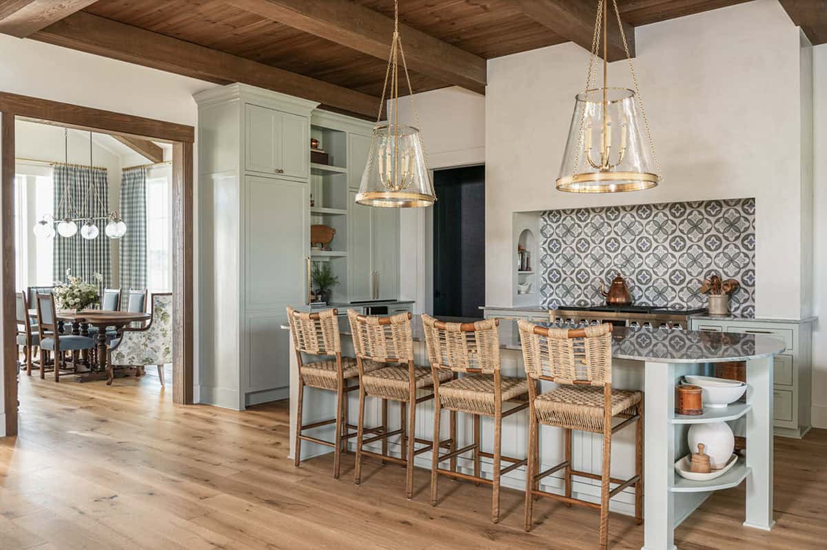 Bright and airy kitchen with farmhouse-inspired design, featuring wooden barstools, a patterned backsplash, and pendant lighting
