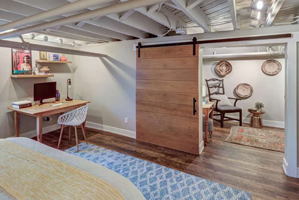 Eclectic Basement Guest Bedroom with a work desk and sliding barn door