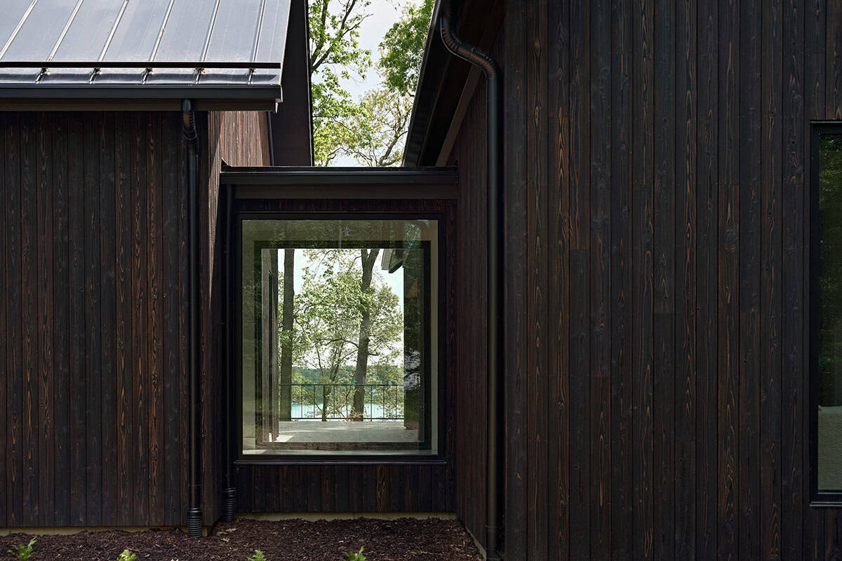 lake house exterior with dark shou sugi ban siding and a glass connector bridge