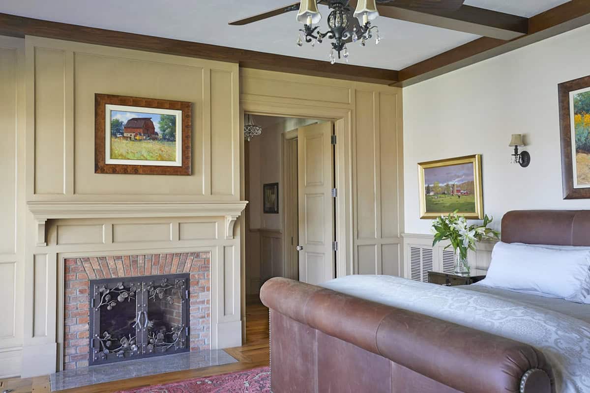 farmhouse style bedroom with wide plank wood floors and brick surround fireplace
