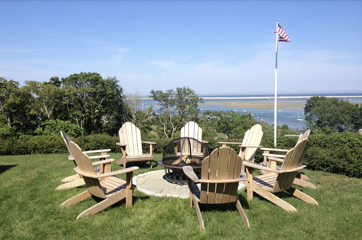 adirondack chairs around a fire pit overlooking the water