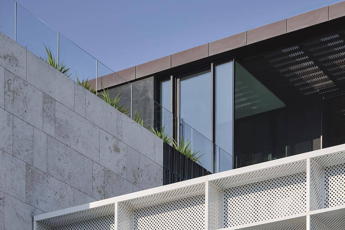 A modern concrete building featuring a balcony with vibrant green plants