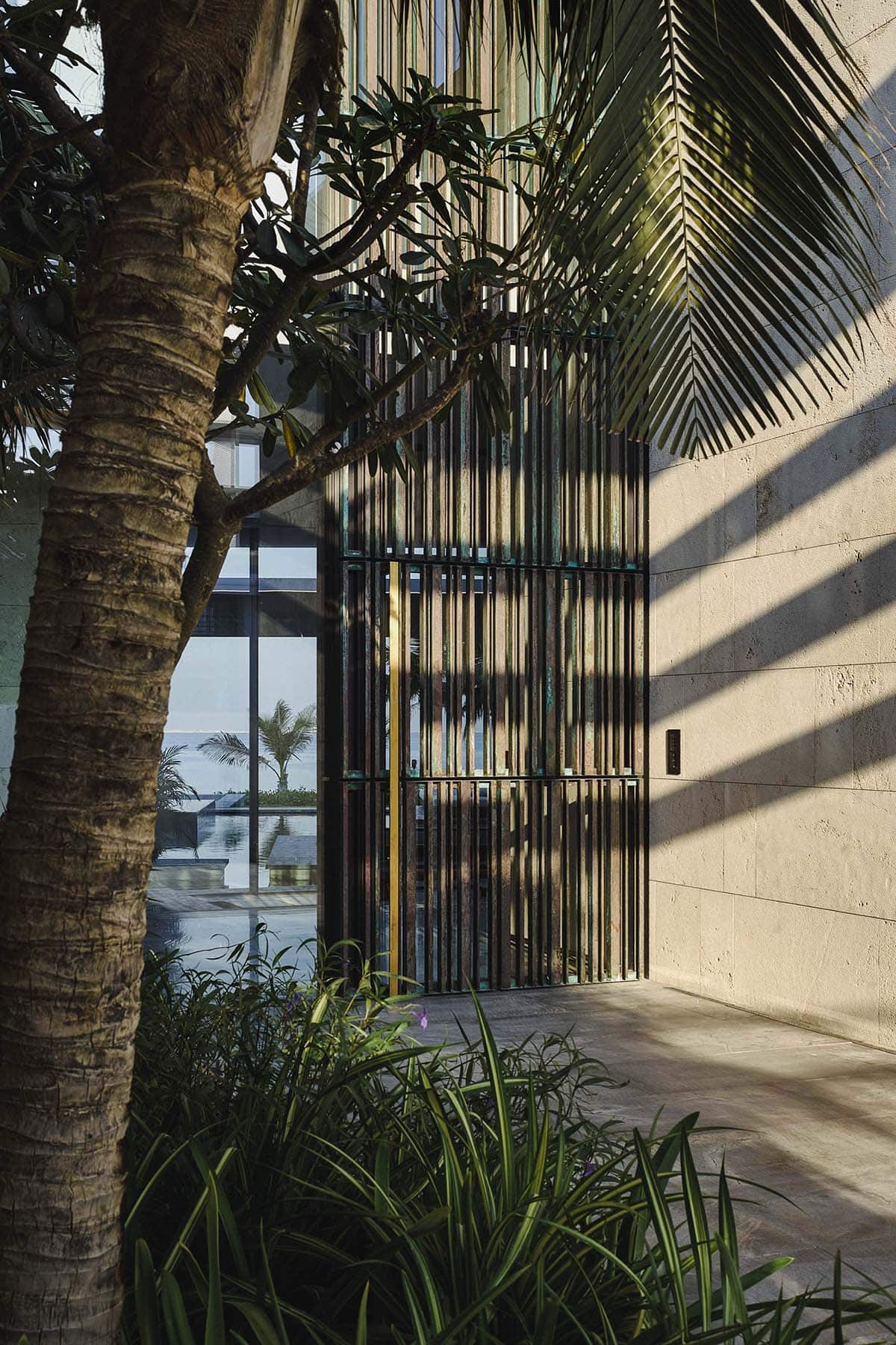 A modern building featuring a large glass door, surrounded by palm trees