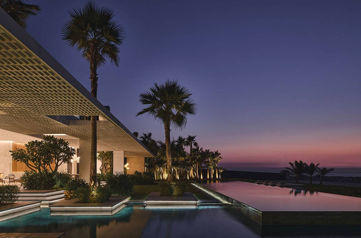 A modern home with a pool and palm trees, illuminated by dusk's soft light, creating a serene evening atmosphere