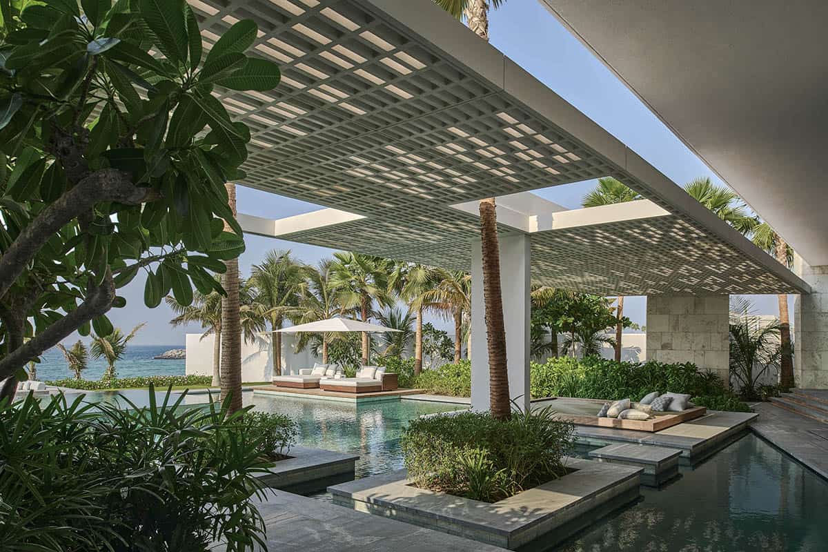 A sleek pool area overlooking the ocean, featuring modern lounge chairs and a clear blue sky