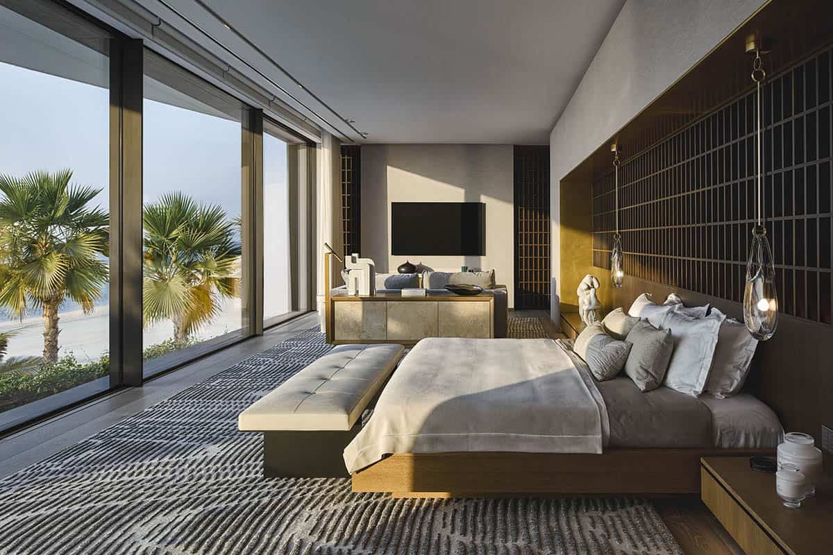 A modern bedroom featuring a large window with a view of the ocean, showcasing serene coastal scenery