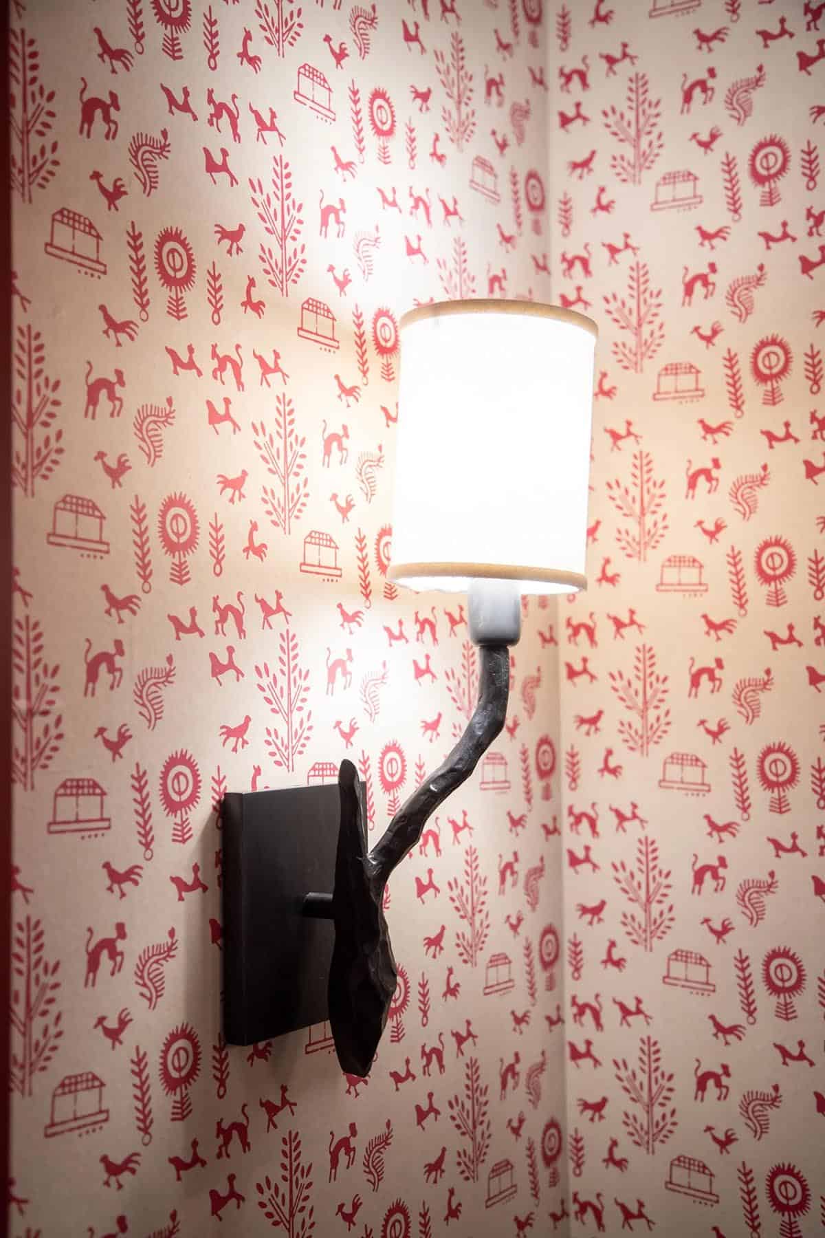 powder room with wallpaper and a wall sconce