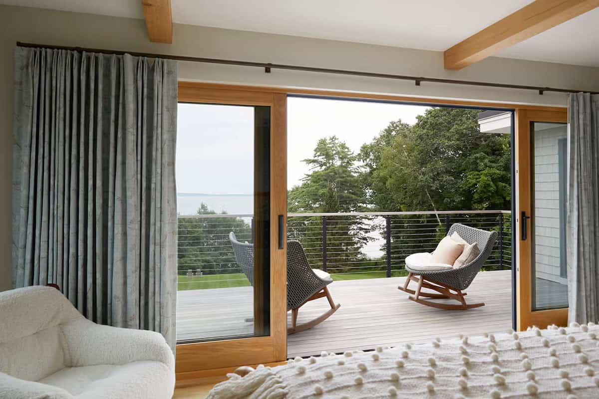 modern coastal style bedroom with sliding glass doors leading to a private balcony