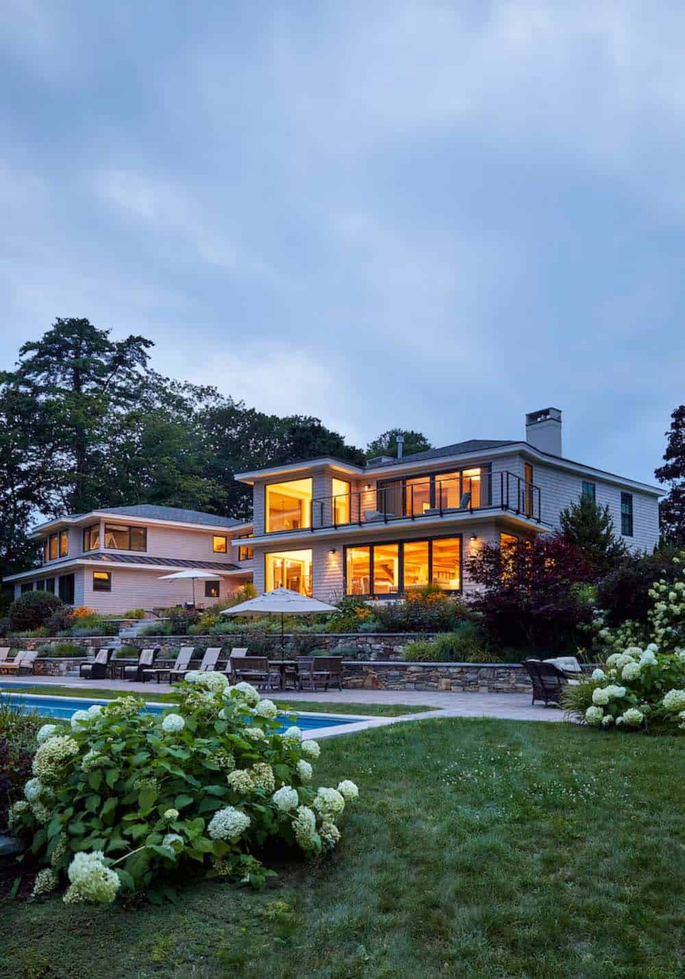 modern coastal home exterior landscape with a pool at dusk