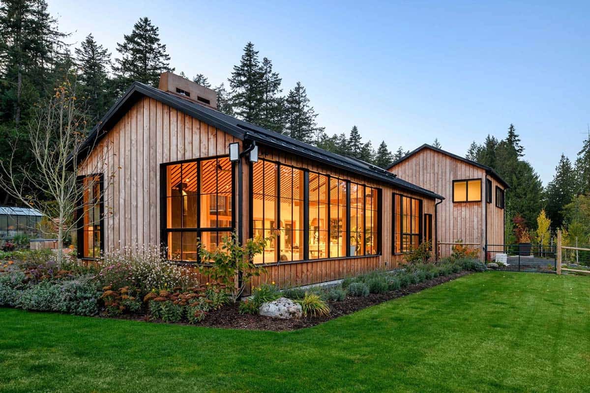 Modern rustic home with large glass windows and integrated wood storage.